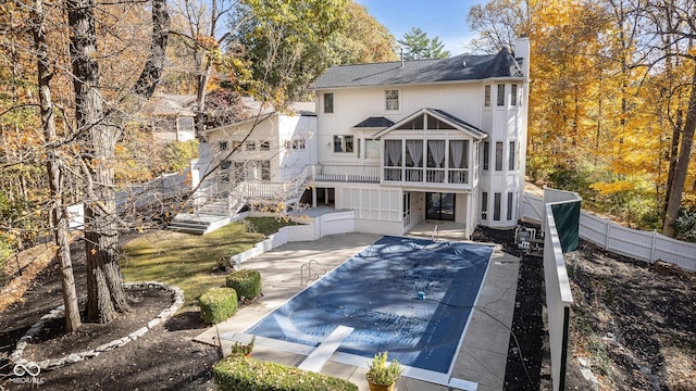 back of property with a patio, a covered pool, and a sunroom