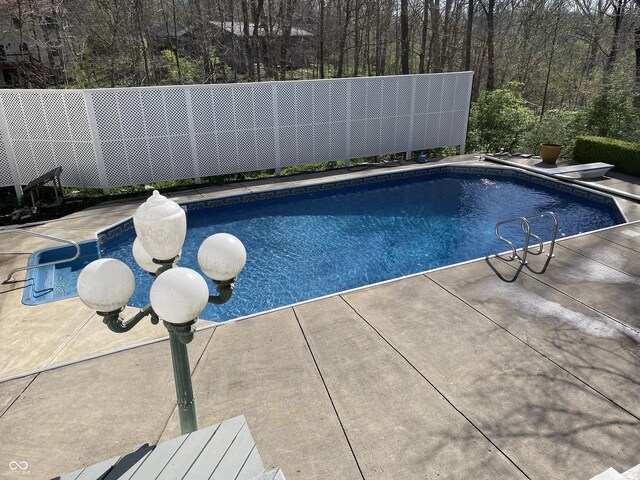 outdoor pool with a diving board and a patio area