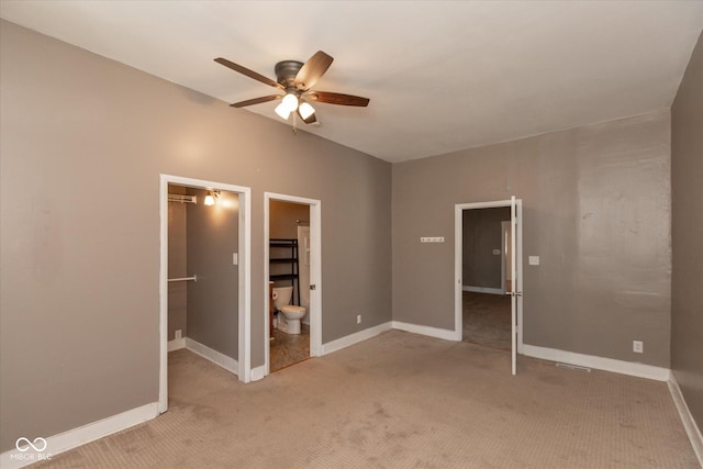 unfurnished bedroom featuring a spacious closet, light colored carpet, and baseboards