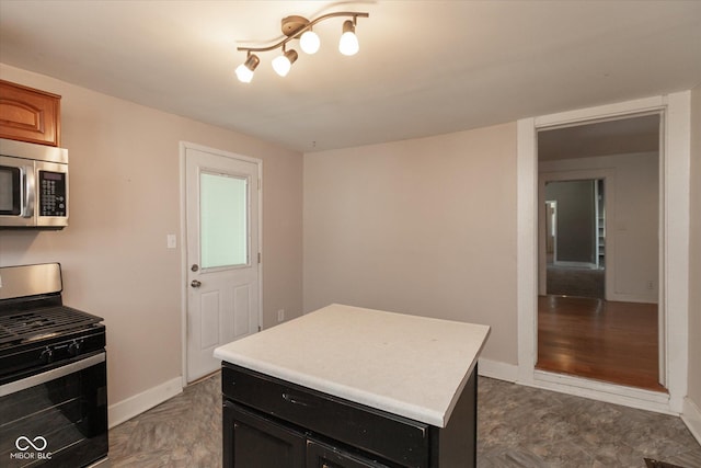 kitchen featuring dark cabinetry, stainless steel appliances, light countertops, and baseboards