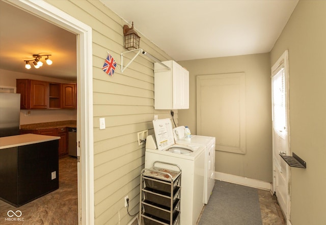 washroom with washing machine and dryer, cabinet space, and baseboards