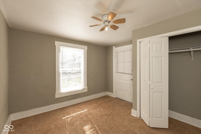 unfurnished bedroom featuring carpet, baseboards, a closet, and ceiling fan