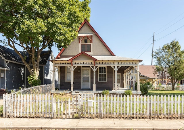 victorian home featuring a fenced front yard and covered porch