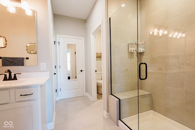 bathroom with a shower with door, vanity, toilet, and tile patterned floors