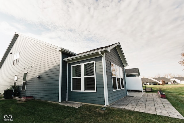 view of property exterior with a patio area and a lawn