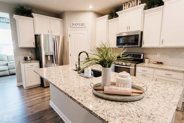 kitchen featuring appliances with stainless steel finishes, dark hardwood / wood-style floors, white cabinetry, and tasteful backsplash