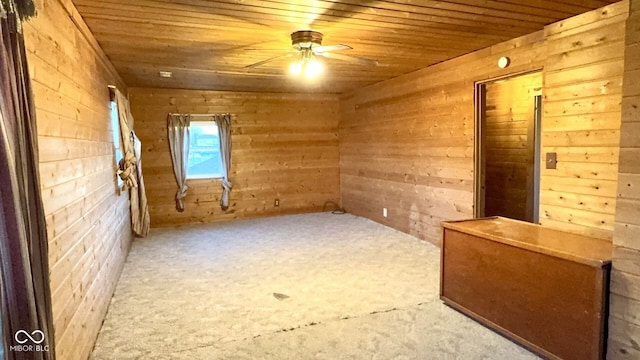 empty room featuring wood ceiling, ceiling fan, and wood walls