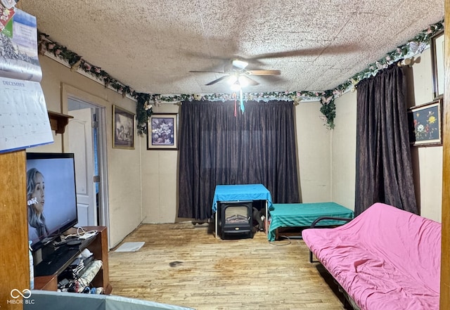 bedroom featuring ceiling fan, hardwood / wood-style flooring, and a textured ceiling