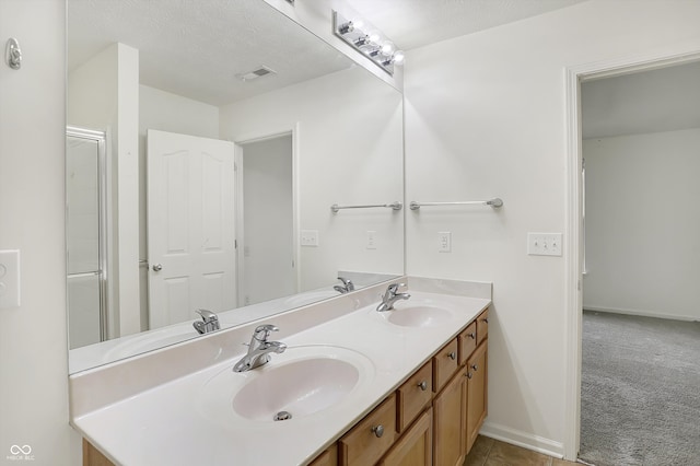 bathroom with vanity, a textured ceiling, and walk in shower