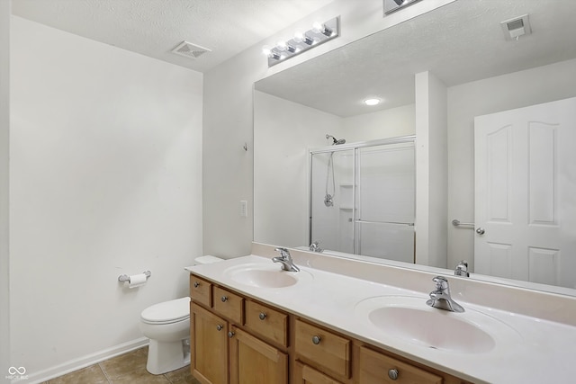 bathroom featuring toilet, tile patterned flooring, a shower with shower door, vanity, and a textured ceiling