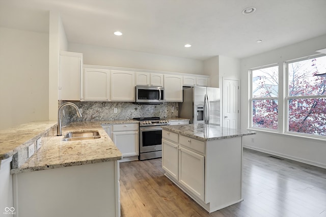 kitchen featuring backsplash, sink, white cabinetry, appliances with stainless steel finishes, and light hardwood / wood-style floors