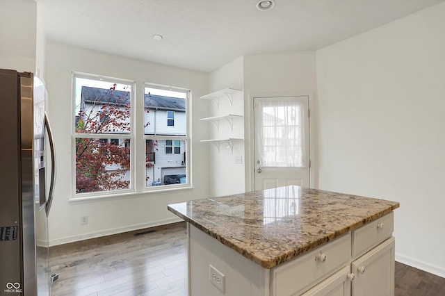 kitchen with hardwood / wood-style flooring, a healthy amount of sunlight, a center island, and stainless steel fridge