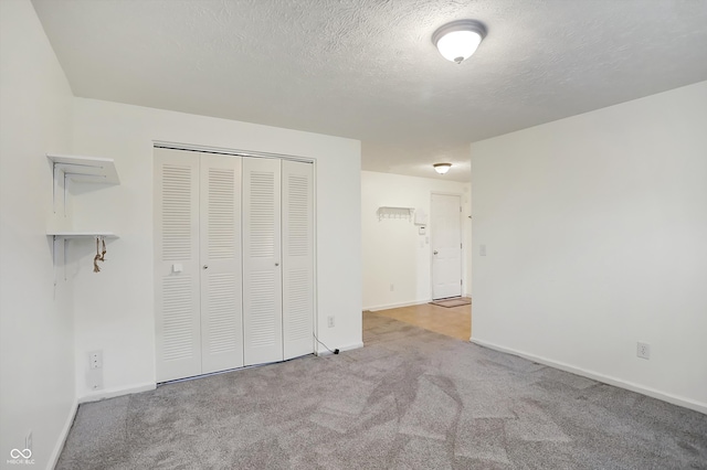 unfurnished bedroom with a closet, a textured ceiling, and light colored carpet