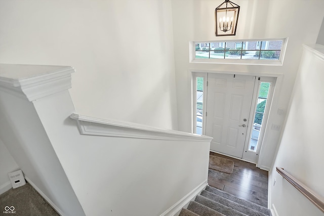 entrance foyer featuring dark wood-type flooring, a towering ceiling, and an inviting chandelier