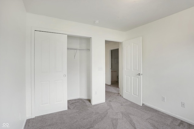 unfurnished bedroom with a closet and light carpet