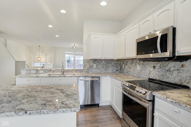 kitchen with hanging light fixtures, stainless steel appliances, sink, white cabinets, and dark hardwood / wood-style flooring