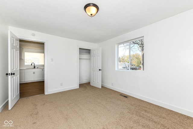 unfurnished bedroom featuring a closet, sink, and carpet flooring