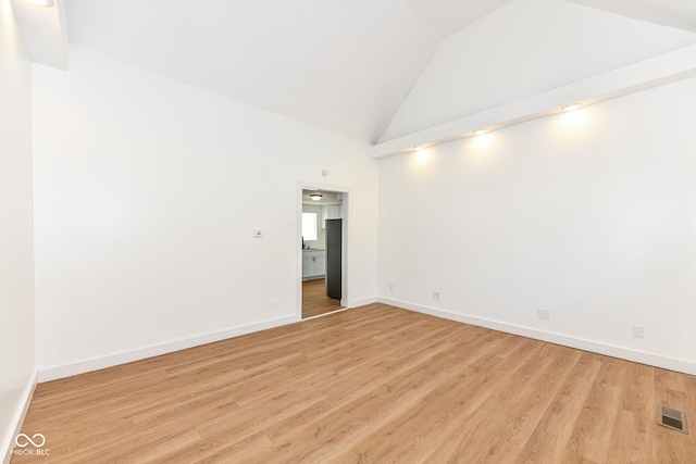 spare room with high vaulted ceiling and light wood-type flooring