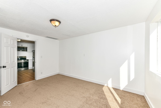 unfurnished room featuring carpet flooring and a textured ceiling