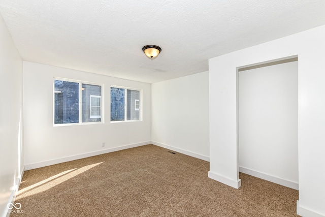 unfurnished room featuring carpet and a textured ceiling