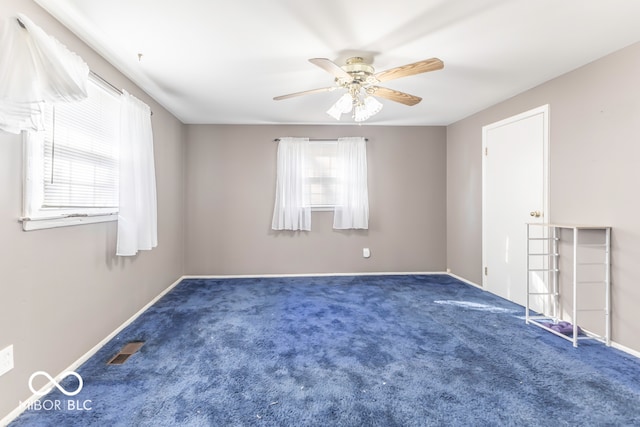 spare room featuring dark carpet and ceiling fan