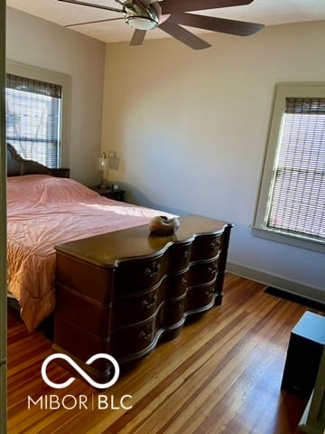 bedroom featuring multiple windows, hardwood / wood-style flooring, and ceiling fan