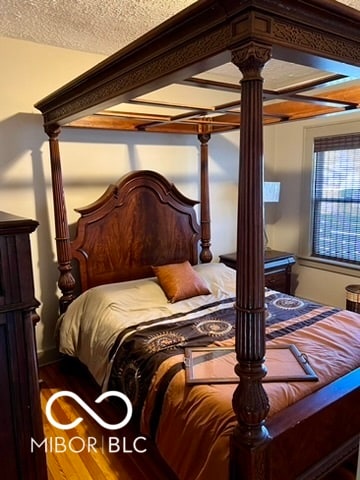 bedroom featuring hardwood / wood-style floors, decorative columns, and a textured ceiling