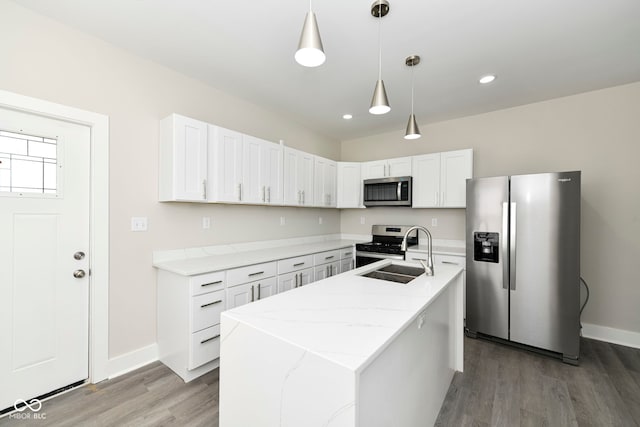 kitchen featuring sink, stainless steel appliances, decorative light fixtures, hardwood / wood-style flooring, and a kitchen island with sink