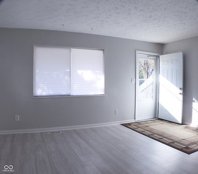 empty room with hardwood / wood-style floors and a textured ceiling