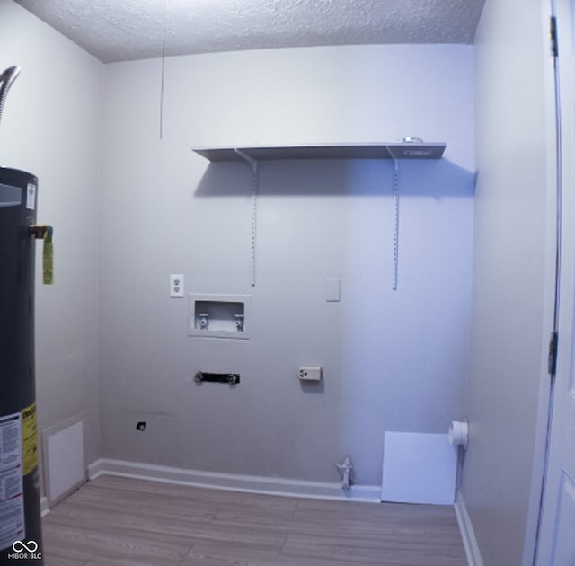 washroom with water heater, hookup for a washing machine, a textured ceiling, and hardwood / wood-style flooring