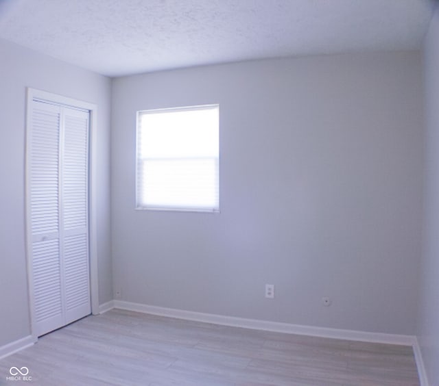 unfurnished bedroom with a closet, light wood-type flooring, and a textured ceiling