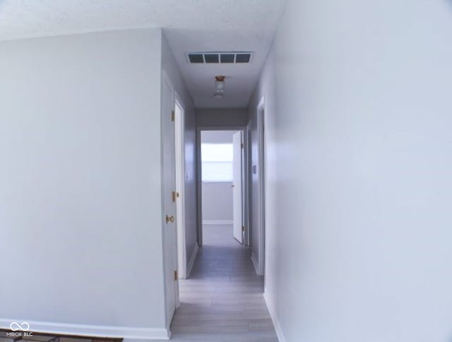 hall with a textured ceiling and hardwood / wood-style flooring