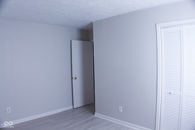 unfurnished bedroom with hardwood / wood-style flooring, a textured ceiling, and a closet