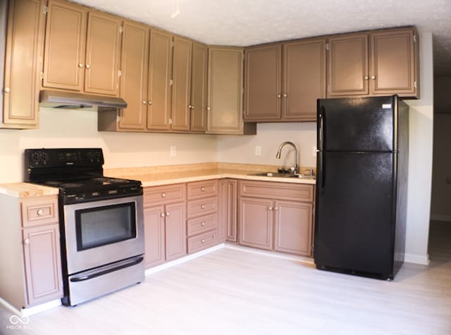 kitchen featuring electric range oven, light hardwood / wood-style floors, black fridge, and sink