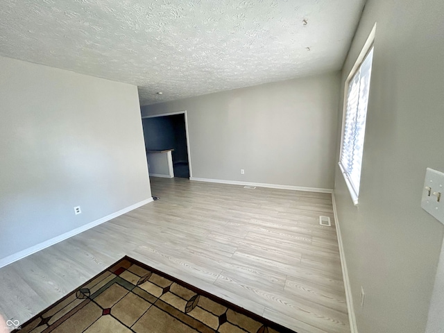 spare room featuring light hardwood / wood-style floors and a textured ceiling