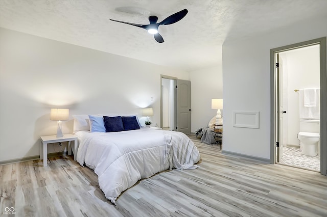 bedroom featuring light hardwood / wood-style flooring, a textured ceiling, ceiling fan, and ensuite bath