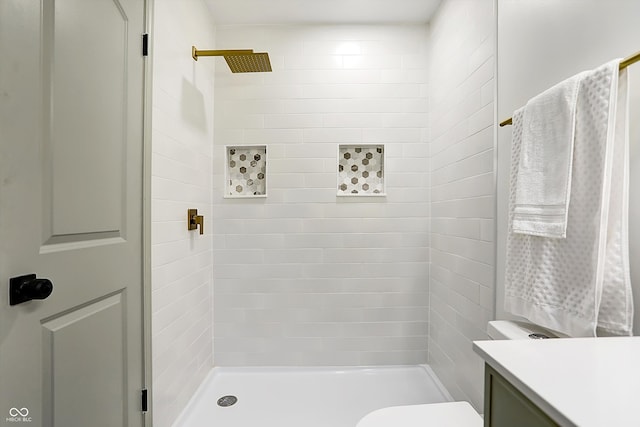 bathroom featuring vanity, toilet, and tiled shower