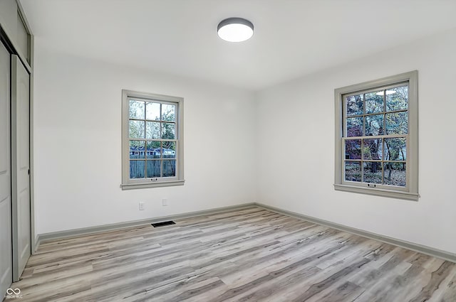 unfurnished bedroom with light wood-type flooring and a closet