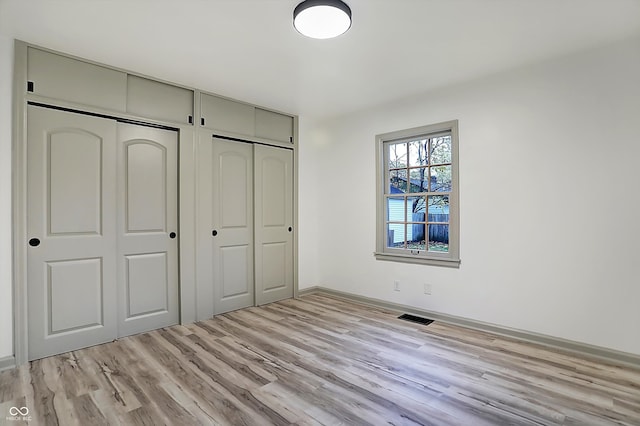 unfurnished bedroom with multiple closets and light hardwood / wood-style floors