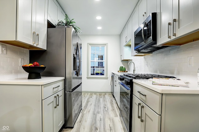 kitchen with white cabinetry, appliances with stainless steel finishes, decorative backsplash, and light hardwood / wood-style floors