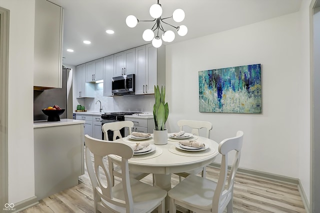 dining area featuring light hardwood / wood-style floors, sink, and an inviting chandelier