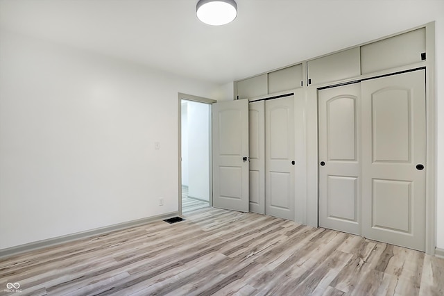 unfurnished bedroom featuring light wood-type flooring and two closets