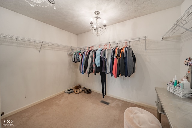 spacious closet featuring a chandelier and light colored carpet