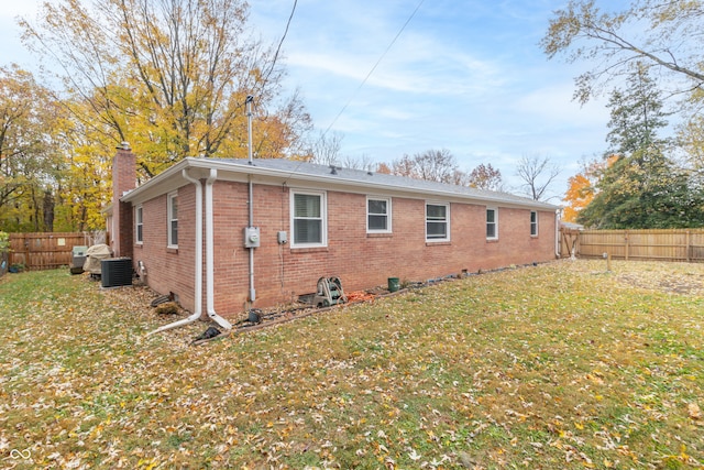 rear view of property with cooling unit and a yard