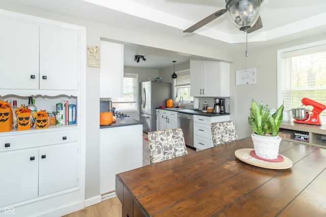 kitchen featuring light wood-type flooring, appliances with stainless steel finishes, a raised ceiling, white cabinets, and ceiling fan