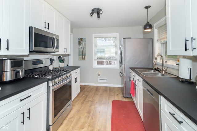 kitchen with appliances with stainless steel finishes, light hardwood / wood-style floors, and white cabinets