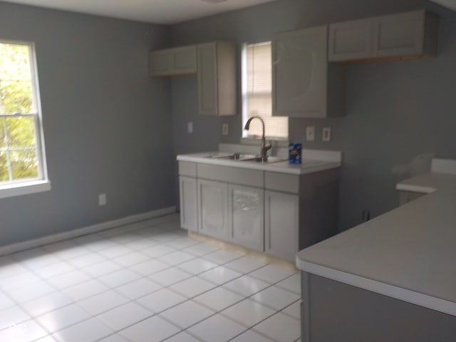 kitchen with gray cabinets, light tile patterned floors, and sink