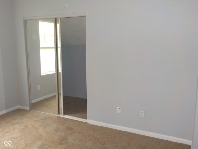 unfurnished bedroom with light carpet and a closet