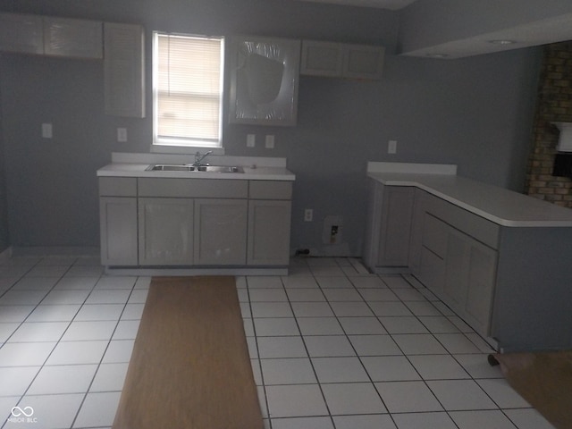 kitchen featuring sink, kitchen peninsula, gray cabinets, and light tile patterned floors