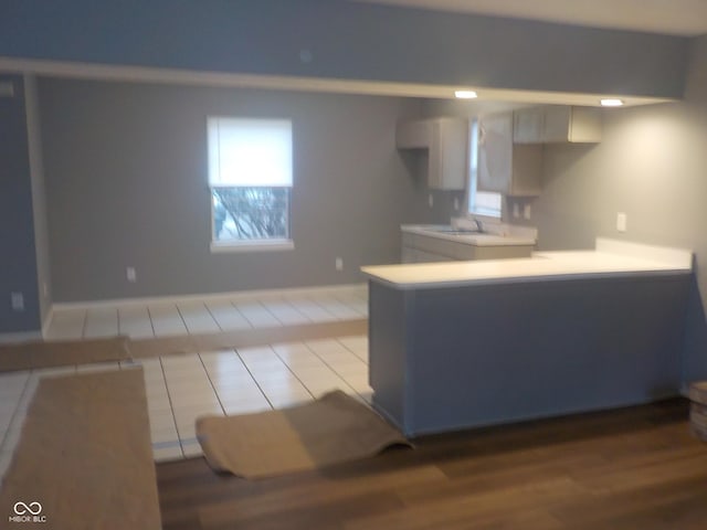 kitchen with sink, kitchen peninsula, white cabinets, and hardwood / wood-style floors